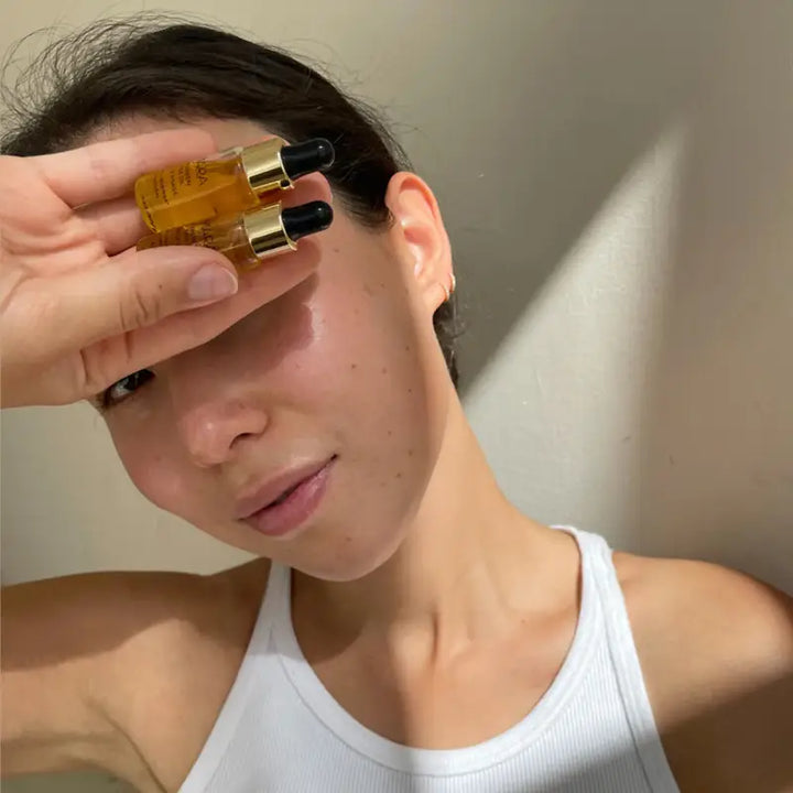 Woman holding two bottles of Mara Algae Retinol Face Oil